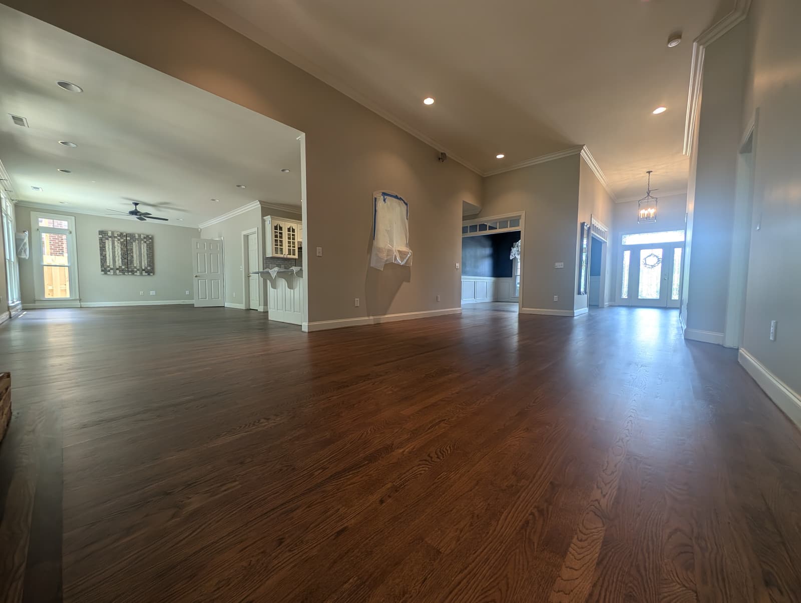 Refinished hardwood running through an open-plan great room to the front foyer, by Forever Flooring
