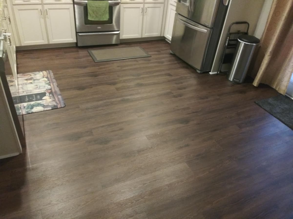 Dark luxury vinyl plank in a kitchen with stainless appliances
