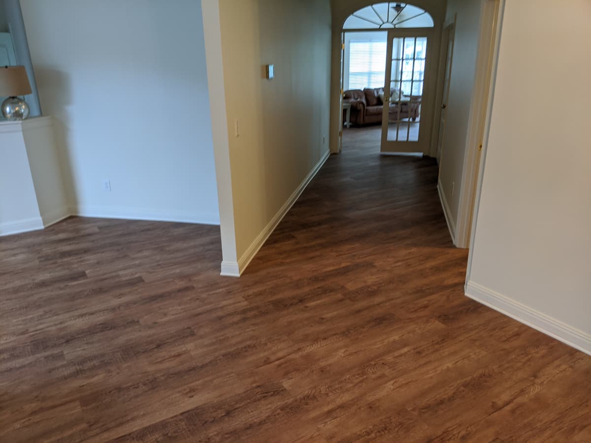 Warm-toned luxury vinyl plank down a hallway through an arched doorway