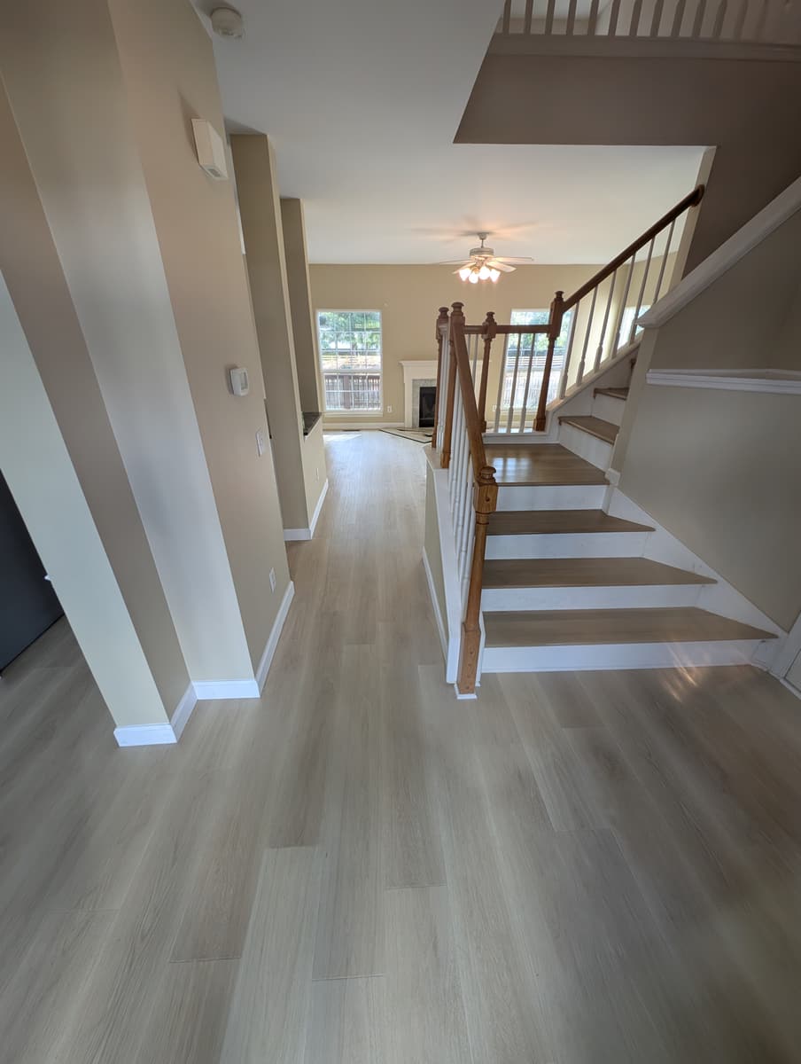 Light luxury vinyl plank running from a foyer to a staircase