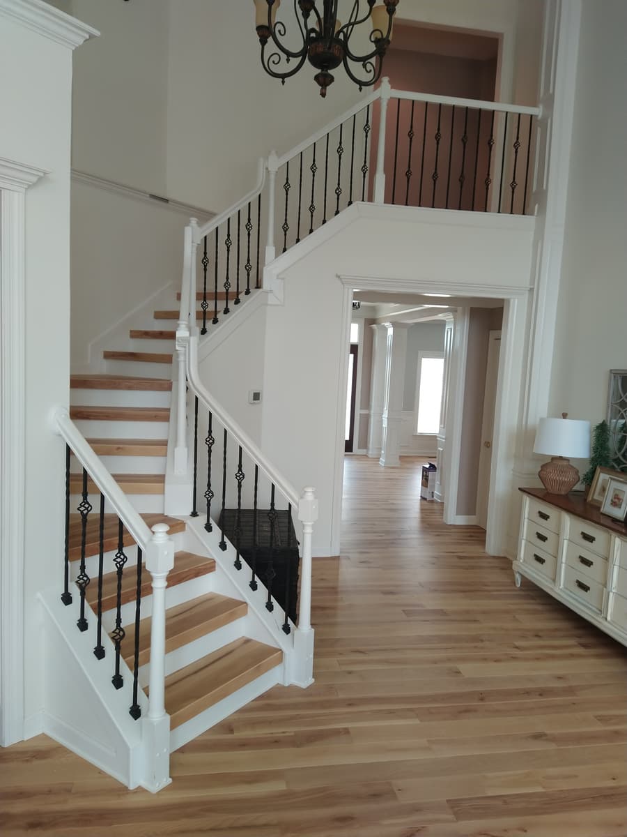 A curved foyer staircase with oak treads, white risers and iron balusters