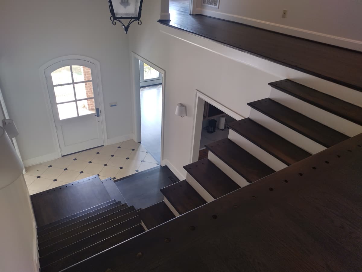 Dark-stained stair treads leading down to a tiled foyer