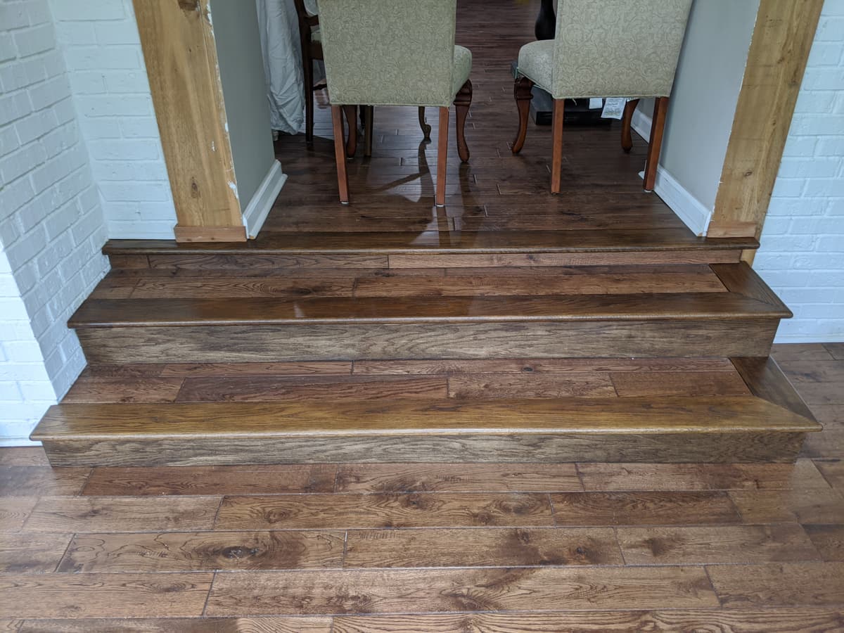 A rustic hand-scraped hardwood step-down into a dining area