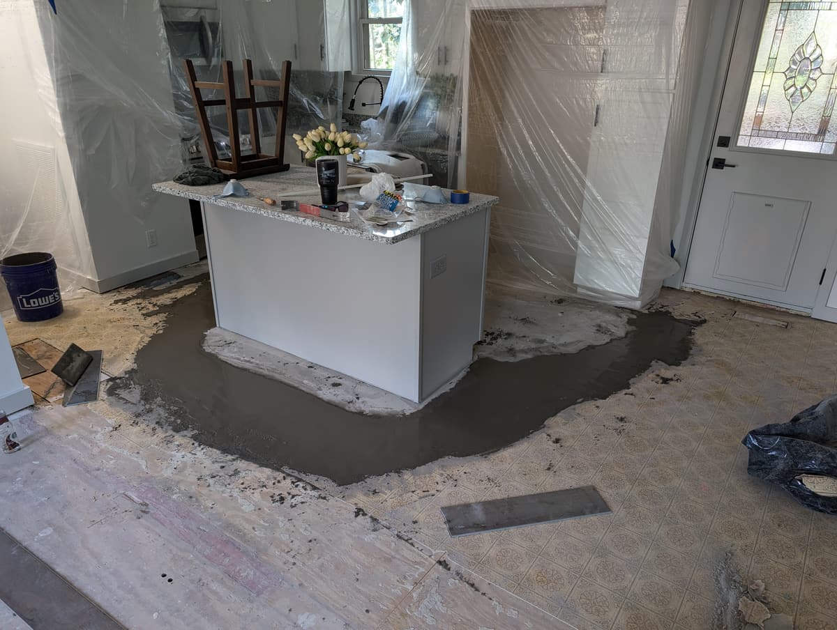 Self-leveling compound poured around a kitchen island to flatten the subfloor